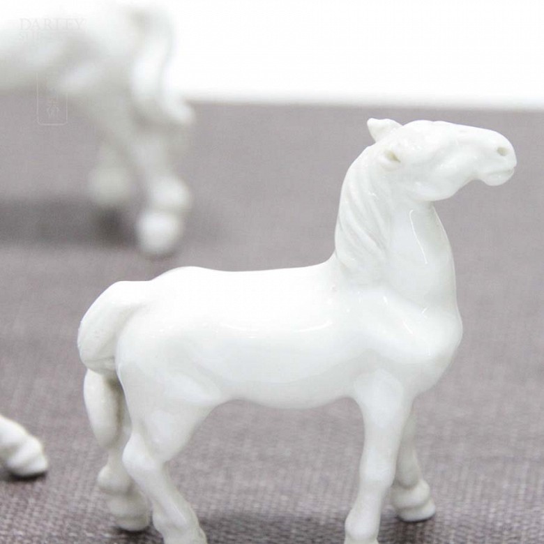 Seven miniature white porcelain horses.