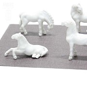 Seven miniature white porcelain horses.