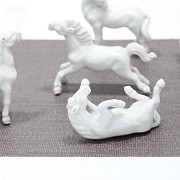 Seven miniature white porcelain horses.