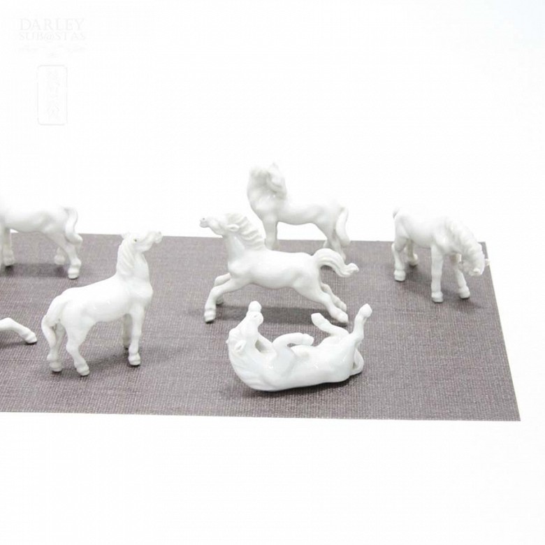 Seven miniature white porcelain horses.