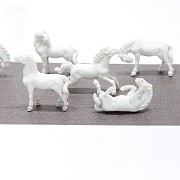 Seven miniature white porcelain horses.