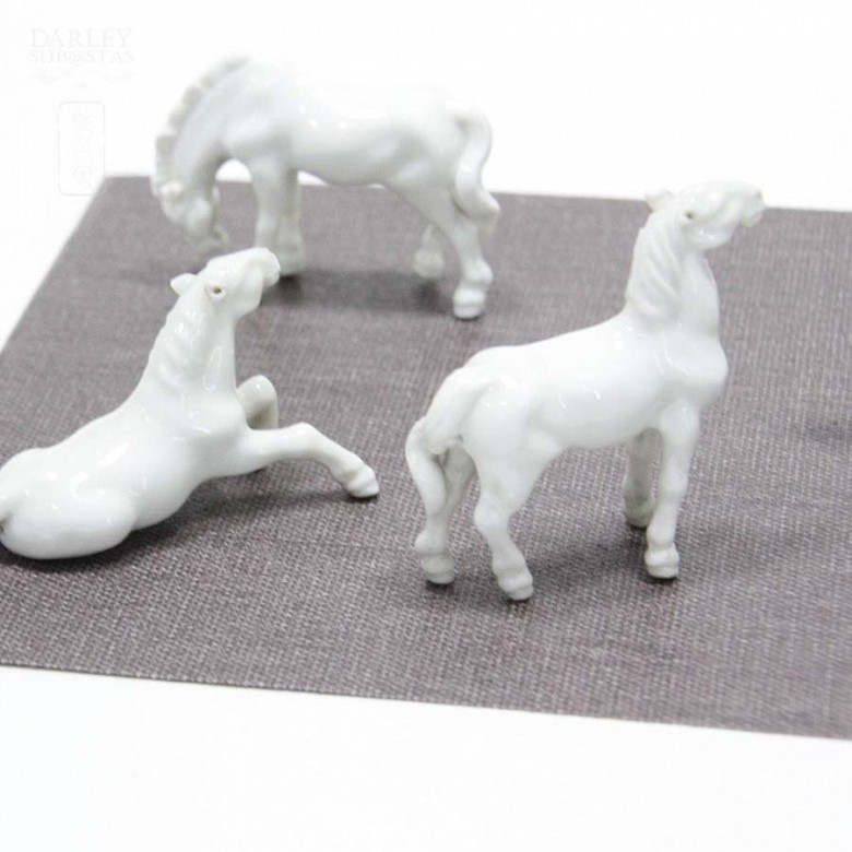 Seven miniature white porcelain horses.